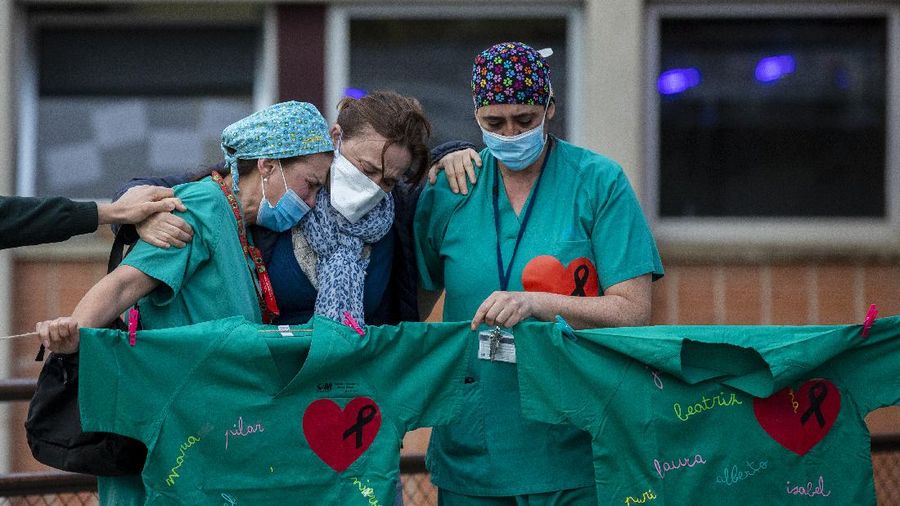Health workers cry during a memorial for their co-worker Esteban, a male nurse that died of the coronavirus disease, at the Severo Ochoa Hospital in Leganes in Leganes, Spain, Friday, April 10, 2020. The new coronavirus causes mild or moderate symptoms for most people, but for some, especially older adults and people with existing health problems, it can cause more severe illness or death. (AP Photo/Manu Fernandez)
