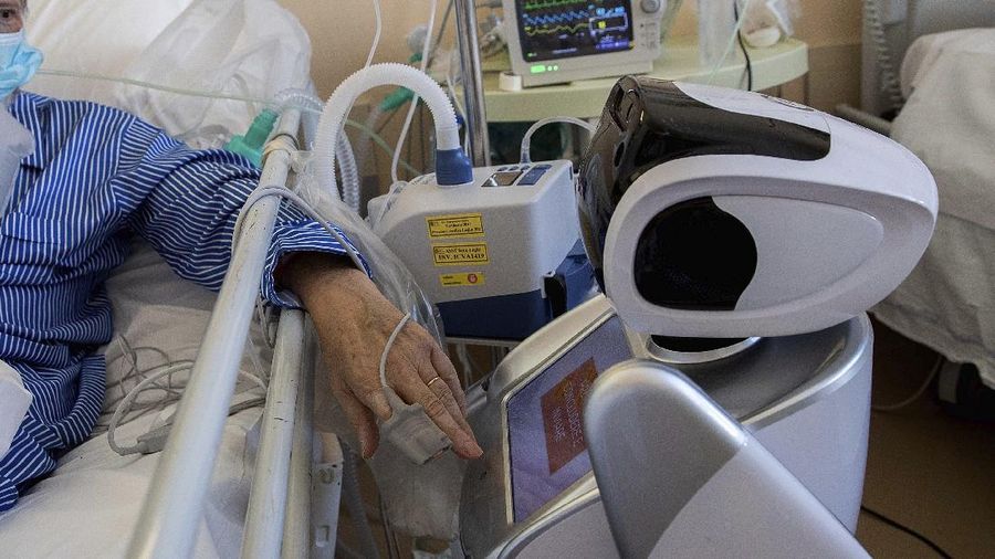 Deputy head of the intensive care unit Flavio Tangian, prepares a robot at 'Ospedale di Circolo' hospital, in Varese, Italy, Wednesday, April 8, 2020. Six robots will help healthcare professionals assist Covid-19 patients, one robot for every two patients to maximize monitoring and assistance. The new coronavirus causes mild or moderate symptoms for most people, but for some, especially older adults and people with existing health problems, it can cause more severe illness or death. (AP Photo/Luca Bruno)