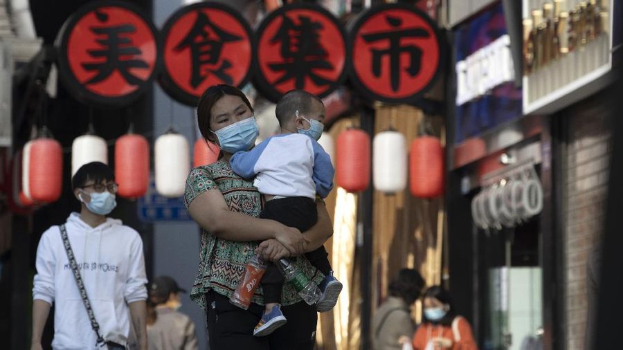 Residents wearing masks to help curb the spread the coronavirus walk along a retail street in Wuhan in central China's Hubei province on Thursday, April 9, 2020. Released from their apartments after a 2 1/2-month quarantine, residents of the city where the coronavirus pandemic began are cautiously returning to shopping and strolling in the street but say they still go out little and keep children home while they wait for schools to reopen. (AP Photo/Ng Han Guan)