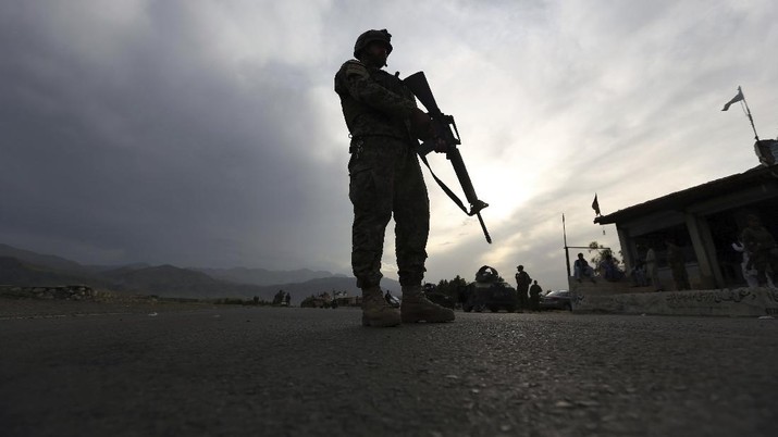 FILE - In this Saturday, April 4, 2020 file photo, an Afghan National Army soldier stands guard at a checkpoint to enforce a curfew for the the fight against the coronavirus, on the Jalalabad-Kabul highway, in the Laghman province, east of Kabul, Afghanistan. (AP Photo/Rahmat Gul, File)
