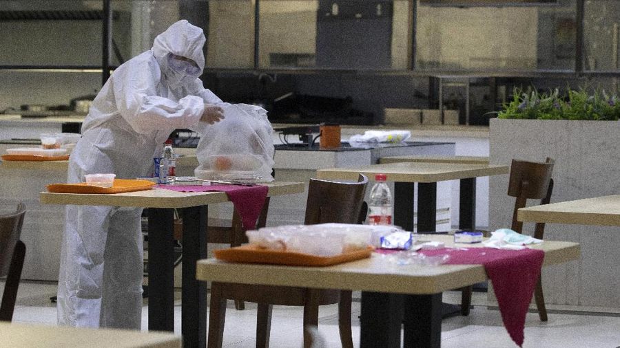 Seorang pekerja dengan menggunakan alat pelindung membersihkan bekas makanan di Universitas Wuhan di Wuhan di provinsi Hubei China (AP/Ng Han Guan)