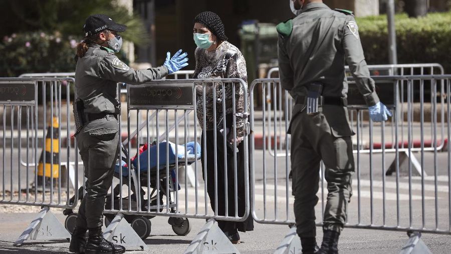 FILE - In this Friday, April 3, 2020 file photo, Israeli border police officers block a main road following the government's measures to help stop the spread of the coronavirus, in Bnei Brak, a suburb of Tel Aviv, Israel. By Friday, Bnei Brak had become the country's worst hot spot and now resembles a ghost town. (AP Photo/Oded Balilty, File)