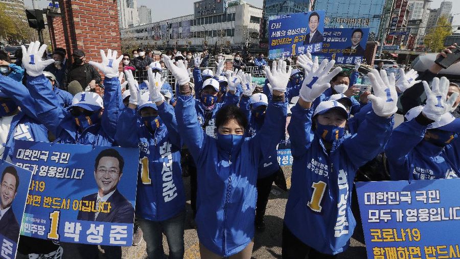 The ruling Democratic Party's supporters wearing face masks to help protect against the spread of the new coronavirus wave their hands during a campaign for the upcoming parliamentary election in Seoul, South Korea, Tuesday, April 14, 2020. The elections will be held on April 15 at about 14,300 polling stations all over the nation to pick lawmakers.(AP Photo/Ahn Young-joon)