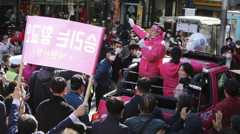The ruling Democratic Party's supporters wearing face masks to help protect against the spread of the new coronavirus wave their hands during a campaign for the upcoming parliamentary election in Seoul, South Korea, Tuesday, April 14, 2020. The elections will be held on April 15 at about 14,300 polling stations all over the nation to pick lawmakers.(AP Photo/Ahn Young-joon)