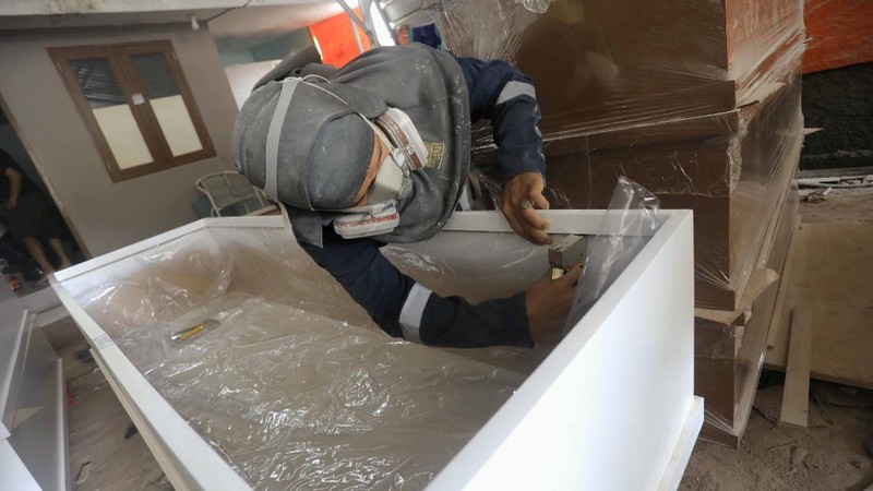 Pekerja memproduksi peti khusus jenazah COVID-19 di Kawasan Ciater, Tangerang Selatan, Banten, Selasa (14/4/2020). Peti mati khusus jenazah COVID-19 tersebut dilapisi alumunium plastik di semua sisi untuk mencegah penyebarannya. (CNBC Indonesia/Andrean Kristianto)