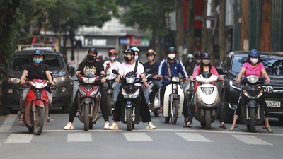 Motorcyclists wearing masks stop at for traffic lights in Hanoi, Vietnam Tuesday, April 14, 2020. The new coronavirus causes mild or moderate symptoms for most people, but for some, especially older adults and people with existing health problems, it can cause more severe illness or death. (AP Photo/Hau Dinh)