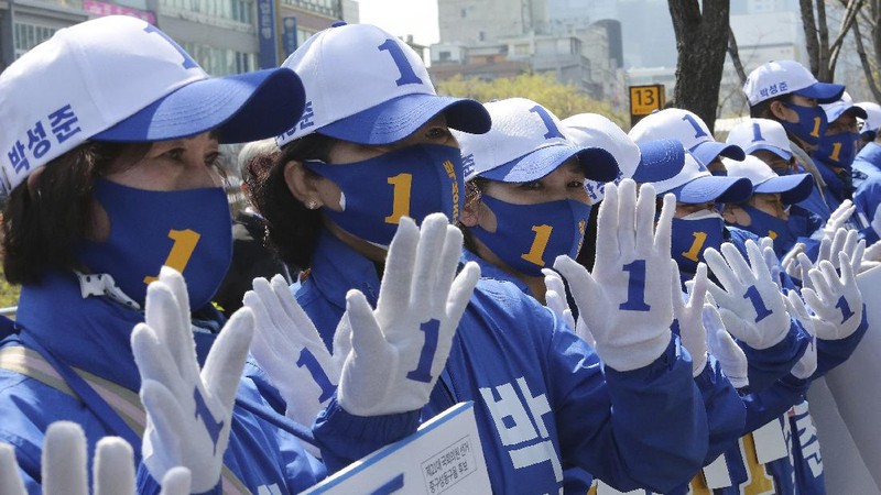 The ruling Democratic Party's supporters wearing face masks to help protect against the spread of the new coronavirus wave their hands during a campaign for the upcoming parliamentary election in Seoul, South Korea, Tuesday, April 14, 2020. The elections will be held on April 15 at about 14,300 polling stations all over the nation to pick lawmakers.(AP Photo/Ahn Young-joon)