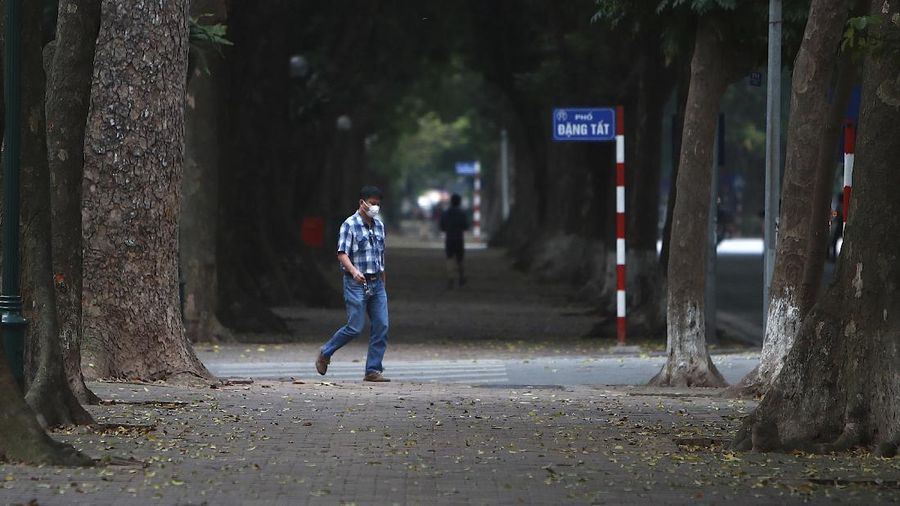 A man wearing a face mask walks on a quiet street in Hanoi, Vietnam, Wednesday, April 1, 2020. Vietnam on Wednesday starts two weeks of social distancing to contain the spread of COVID-19. The new coronavirus causes mild or moderate symptoms for most people, but for some, especially older adults and people with existing health problems, it can cause more severe illness or death. (AP Photo/Hau Dinh)