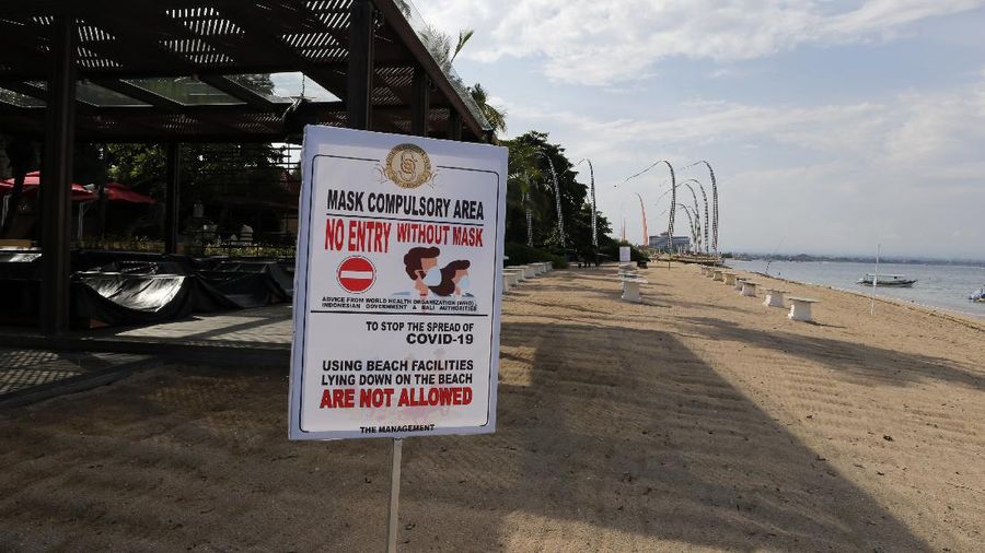 A woman wears a face mask to help stop the spread of the coronavirus as she bicycles down an empty road in Bali, Indonesia, Tuesday, April 14, 2020. Forced apart by the coronavirus pandemic, Southeast Asian leaders linked up by video Tuesday to plot a strategy to overcome a crisis that has threatened their economies and bound millions of people in their homes under lockdowns. (AP Photo/Firdia Lisnawati)