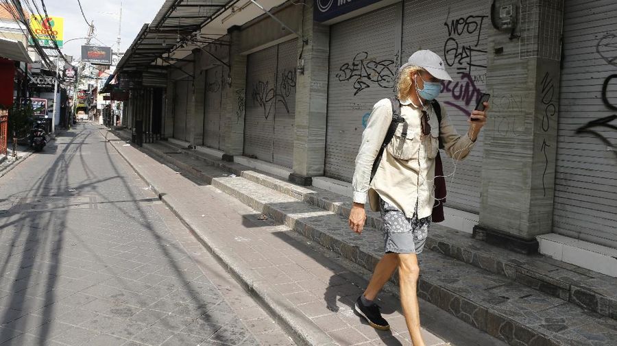 A woman wears a face mask to help stop the spread of the coronavirus as she bicycles down an empty road in Bali, Indonesia, Tuesday, April 14, 2020. Forced apart by the coronavirus pandemic, Southeast Asian leaders linked up by video Tuesday to plot a strategy to overcome a crisis that has threatened their economies and bound millions of people in their homes under lockdowns. (AP Photo/Firdia Lisnawati)