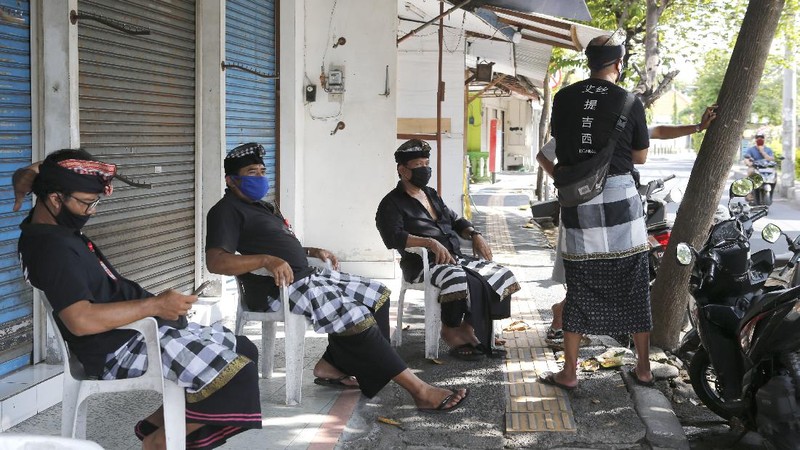 A woman wears a face mask to help stop the spread of the coronavirus as she bicycles down an empty road in Bali, Indonesia, Tuesday, April 14, 2020. Forced apart by the coronavirus pandemic, Southeast Asian leaders linked up by video Tuesday to plot a strategy to overcome a crisis that has threatened their economies and bound millions of people in their homes under lockdowns. (AP Photo/Firdia Lisnawati)