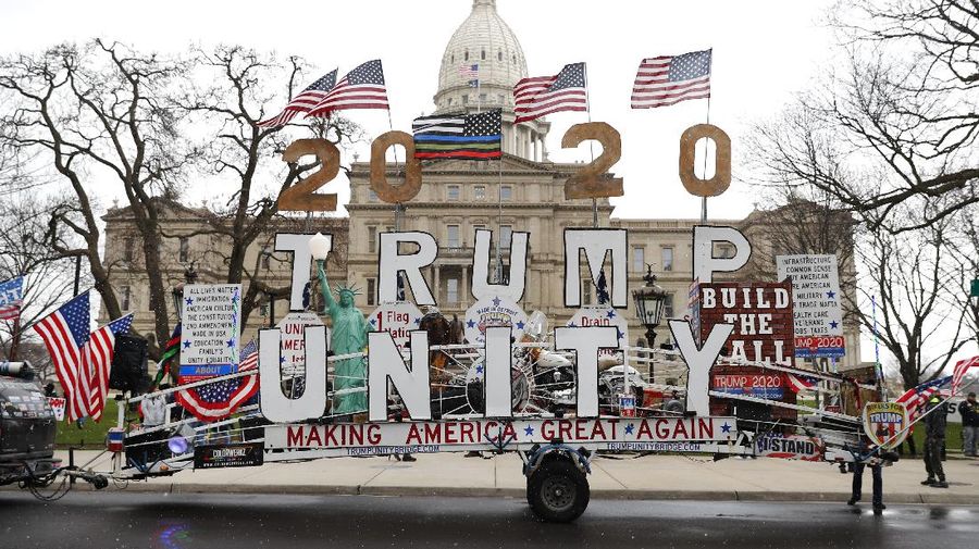 A Trump Unity sign on a trailer is shown parked at a protest in front of the Michigan State Capitol in Lansing, Mich., Wednesday, April 15, 2020. Flag-waving, honking protesters drove past the Michigan Capitol on Wednesday to show their displeasure with Gov. Gretchen Whitmer's orders to keep people at home and businesses locked during the new coronavirus COVID-19 outbreak. (AP Photo/Paul Sancya)