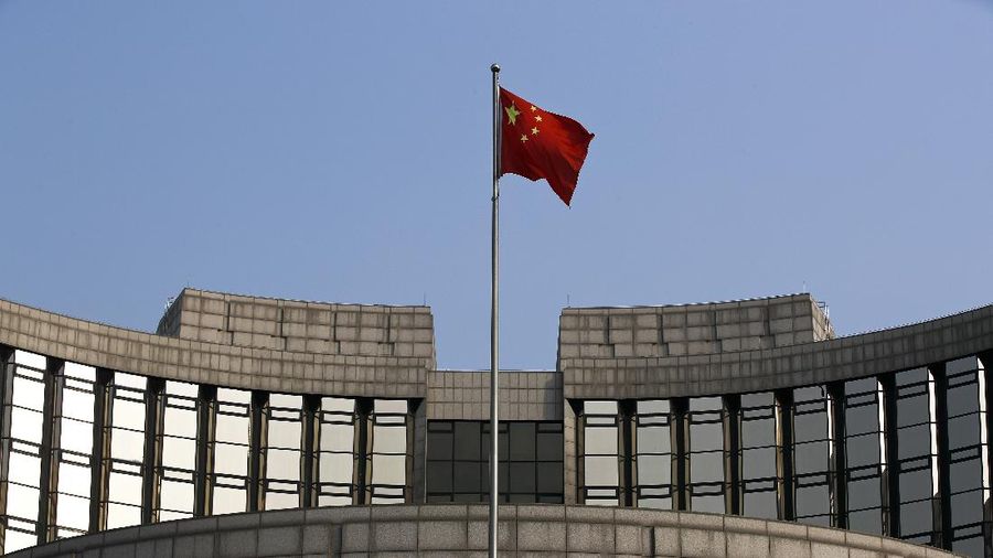 A man walks past China's central bank, or the People's Bank of China, in Beijing, Sunday, March 10, 2019. China's central bank governor Yi Gang says American and Chinese envoys discussed sticking to promises to avoid currency devaluations to boost exports during negotiations aimed at ending a tariff war. (AP Photo/Andy Wong)