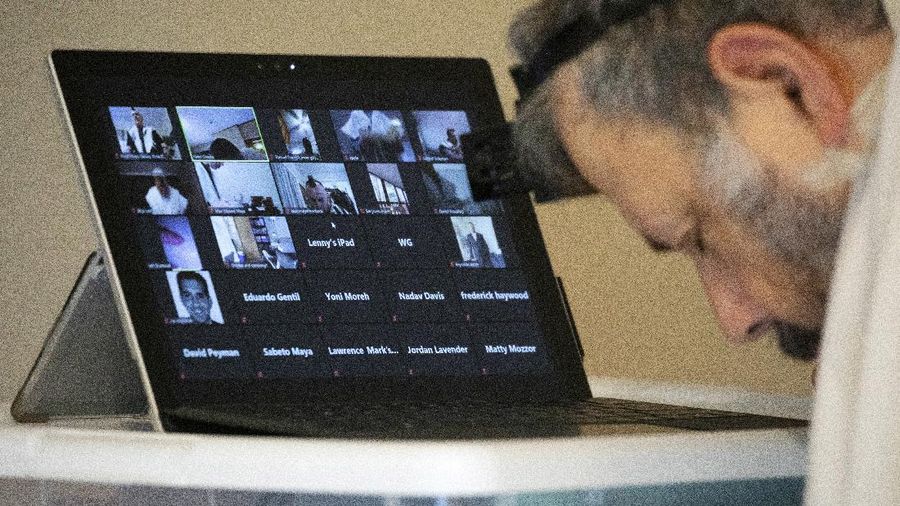 Rabbi Haim Ovadia leads a virtual morning minyan via electronic tablet as 32 people attending his Zoom meeting pray with him during a virtual morning minyan transmitted from Ovadia's home in Potomac Md., Monday, April 6, 2020. Ovadia started the virtual morning minyan, daily prayers that typically require the physical presence of ten adult Jews in the same room, after coronavirus concerns closed many synagogues. He also has an afternoon minyan and classes online. 