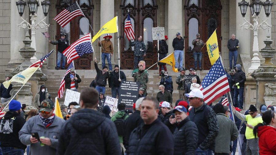 A Trump Unity sign on a trailer is shown parked at a protest in front of the Michigan State Capitol in Lansing, Mich., Wednesday, April 15, 2020. Flag-waving, honking protesters drove past the Michigan Capitol on Wednesday to show their displeasure with Gov. Gretchen Whitmer's orders to keep people at home and businesses locked during the new coronavirus COVID-19 outbreak. (AP Photo/Paul Sancya)