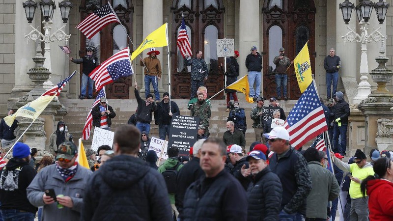 A Trump Unity sign on a trailer is shown parked at a protest in front of the Michigan State Capitol in Lansing, Mich., Wednesday, April 15, 2020. Flag-waving, honking protesters drove past the Michigan Capitol on Wednesday to show their displeasure with Gov. Gretchen Whitmer's orders to keep people at home and businesses locked during the new coronavirus COVID-19 outbreak. (AP Photo/Paul Sancya)