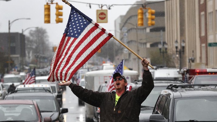 Demo warga Michigan, Amerika Serikat wujud kekecewaan warga setelah Gubernur Michigan memerintahkan warga tetap di rumah guna mencegah penyebaran virus corona (Covid-19). (AP Photo/Paul Sancya) A Trump Unity sign on a trailer is shown parked at a protest in front of the Michigan State Capitol in Lansing, Mich., Wednesday, April 15, 2020. Flag-waving, honking protesters drove past the Michigan Capitol on Wednesday to show their displeasure with Gov. Gretchen Whitmer's orders to keep people at home and businesses locked during the new coronavirus COVID-19 outbreak. (AP Photo/Paul Sancya)