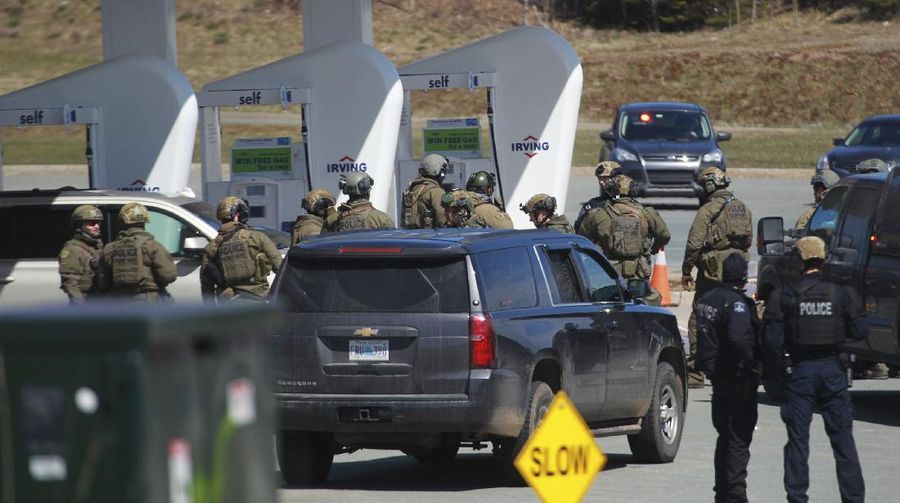 A worker with the medical examiner's office removes a body from a gas bar in Enfield, Nova Scotia, on Sunday, April 19, 2020. A suspect in an active shooter investigation was placed in custody Sunday at an Irving service station in Nova Scotia, after police said there were 