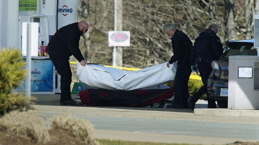 A worker with the medical examiner's office removes a body from a gas bar in Enfield, Nova Scotia, on Sunday, April 19, 2020. A suspect in an active shooter investigation was placed in custody Sunday at an Irving service station in Nova Scotia, after police said there were 