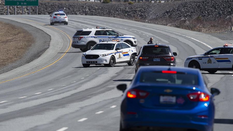 A worker with the medical examiner's office removes a body from a gas bar in Enfield, Nova Scotia, on Sunday, April 19, 2020. A suspect in an active shooter investigation was placed in custody Sunday at an Irving service station in Nova Scotia, after police said there were 