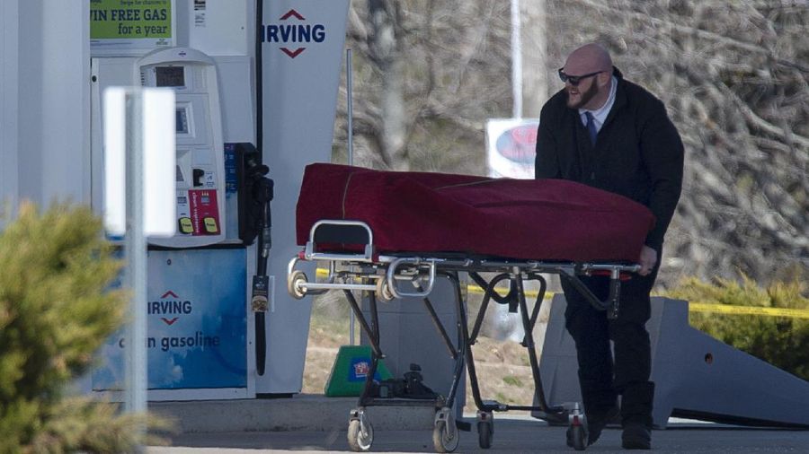 A worker with the medical examiner's office removes a body from a gas bar in Enfield, Nova Scotia, on Sunday, April 19, 2020. A suspect in an active shooter investigation was placed in custody Sunday at an Irving service station in Nova Scotia, after police said there were 