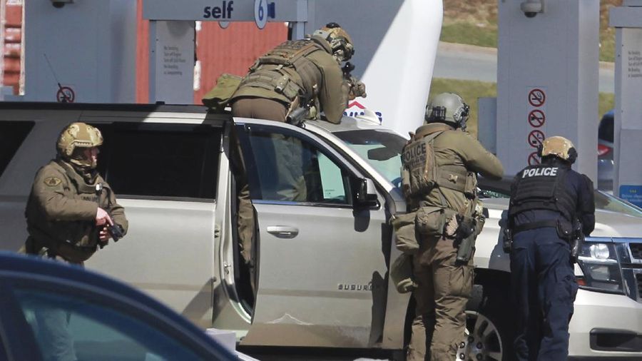 A worker with the medical examiner's office removes a body from a gas bar in Enfield, Nova Scotia, on Sunday, April 19, 2020. A suspect in an active shooter investigation was placed in custody Sunday at an Irving service station in Nova Scotia, after police said there were 