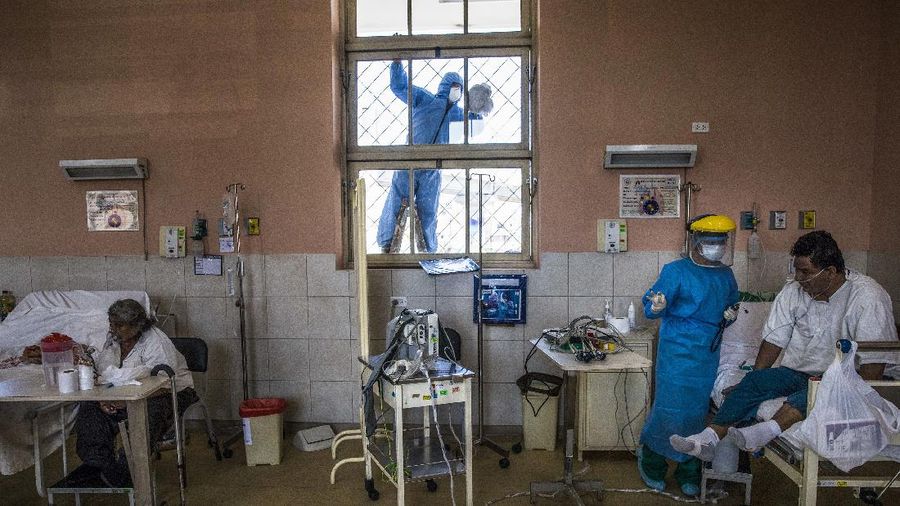 A worker wearing protective gear cleans a window as a nurse tends to a patient inside the intensive care unit for people infected with the coronavirus, at the 2 de Mayo Hospital, in Lima, Peru, April 17, 2020. (AP Photo/Rodrigo Abd)
