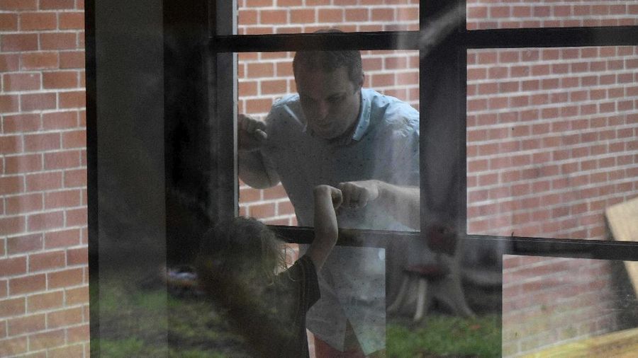 Jason Barnes' fist-bumps with his 6-year-old son, Stiles, against the glass Saturday, April 18, 2020, in Corpus Christi, Texas. Barnes maintains social distancing with his family as long as there are consistent coronavirus cases in the Coastal Bend. (Annie Rice/Corpus Christi Caller-Times via AP)