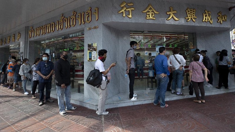 A Thai shopkeeper talks to customer who sold gold necklace to the gold shop in Bangkok, Thailand, Thursday, April 16, 2020. With gold prices rising to a seven-year high, many Thais have been flocking to gold shops to trade in their necklaces, bracelets, rings and gold bars for cash, eager to earn profits during an economic downturn.(AP Photo/Sakchai Lalit)