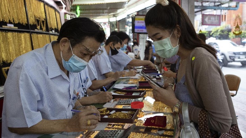 A Thai shopkeeper talks to customer who sold gold necklace to the gold shop in Bangkok, Thailand, Thursday, April 16, 2020. With gold prices rising to a seven-year high, many Thais have been flocking to gold shops to trade in their necklaces, bracelets, rings and gold bars for cash, eager to earn profits during an economic downturn.(AP Photo/Sakchai Lalit)