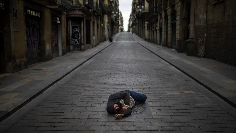 A man sleeps in an empty street during the coronavirus outbreak in Barcelona, Spain, April 17, 2020. (AP Photo/Emilio Morenatti)