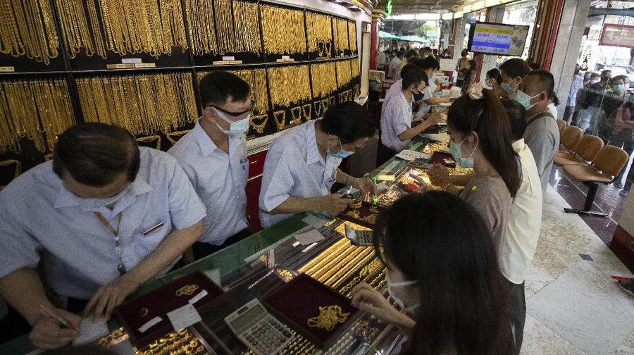 A Thai shopkeeper talks to customer who sold gold necklace to the gold shop in Bangkok, Thailand, Thursday, April 16, 2020. With gold prices rising to a seven-year high, many Thais have been flocking to gold shops to trade in their necklaces, bracelets, rings and gold bars for cash, eager to earn profits during an economic downturn.(AP Photo/Sakchai Lalit)