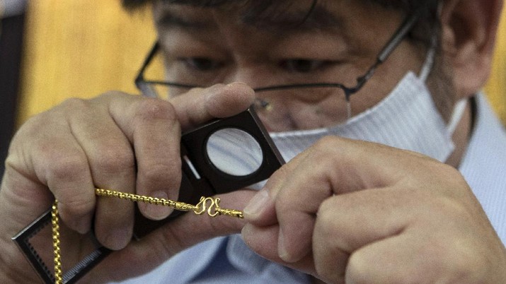 A Thai shopkeeper talks to customer who sold gold necklace to the gold shop in Bangkok, Thailand, Thursday, April 16, 2020. With gold prices rising to a seven-year high, many Thais have been flocking to gold shops to trade in their necklaces, bracelets, rings and gold bars for cash, eager to earn profits during an economic downturn.(AP Photo/Sakchai Lalit)
