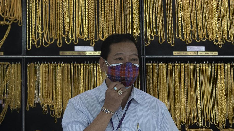 A Thai shopkeeper talks to customer who sold gold necklace to the gold shop in Bangkok, Thailand, Thursday, April 16, 2020. With gold prices rising to a seven-year high, many Thais have been flocking to gold shops to trade in their necklaces, bracelets, rings and gold bars for cash, eager to earn profits during an economic downturn.(AP Photo/Sakchai Lalit)
