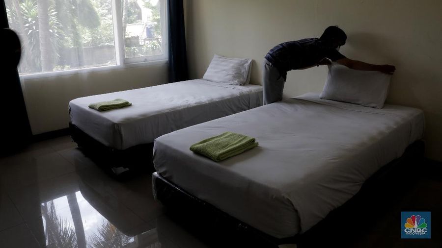 Petugas merapikan ruangan yang akan dijadikan tempat tinggal sementara bagi tenaga medis penanganan Covid-19 di SMKN 57 Jakarta, Rabu (22/4) (CNBC Indonesia/Muhammad Sabki)