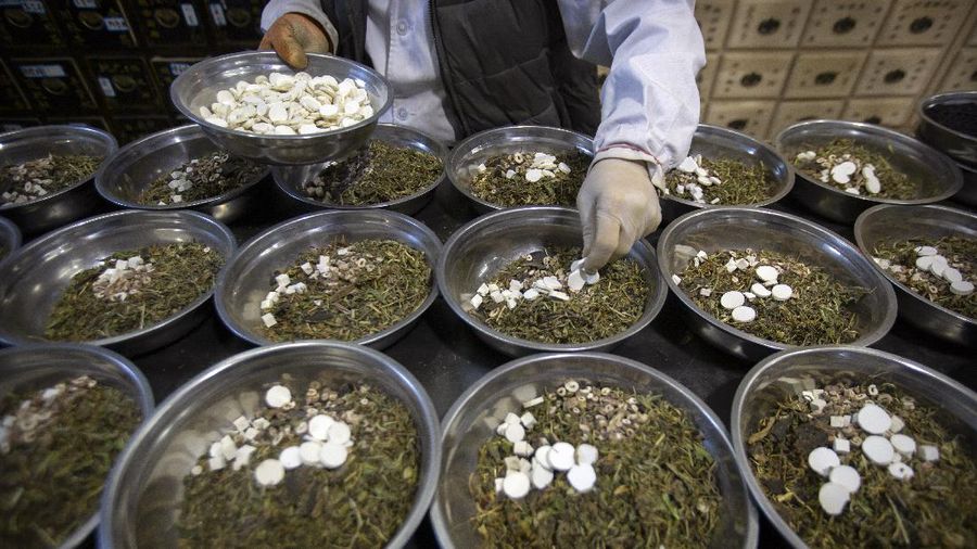 In this March 13, 2020 photo, bowls containing prescriptions for traditional Chinese medicine preparations are stacked on a counter at the Bo Ai Tang traditional Chinese medicine clinic in Beijing. With no approved drugs for the new coronavirus, some people are turning to alternative medicines, often with governments promoting them. (AP Photo/Mark Schiefelbein)