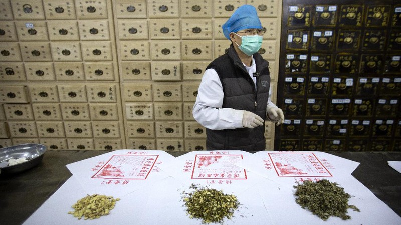 In this March 13, 2020 photo, bowls containing prescriptions for traditional Chinese medicine preparations are stacked on a counter at the Bo Ai Tang traditional Chinese medicine clinic in Beijing. With no approved drugs for the new coronavirus, some people are turning to alternative medicines, often with governments promoting them. (AP Photo/Mark Schiefelbein)
