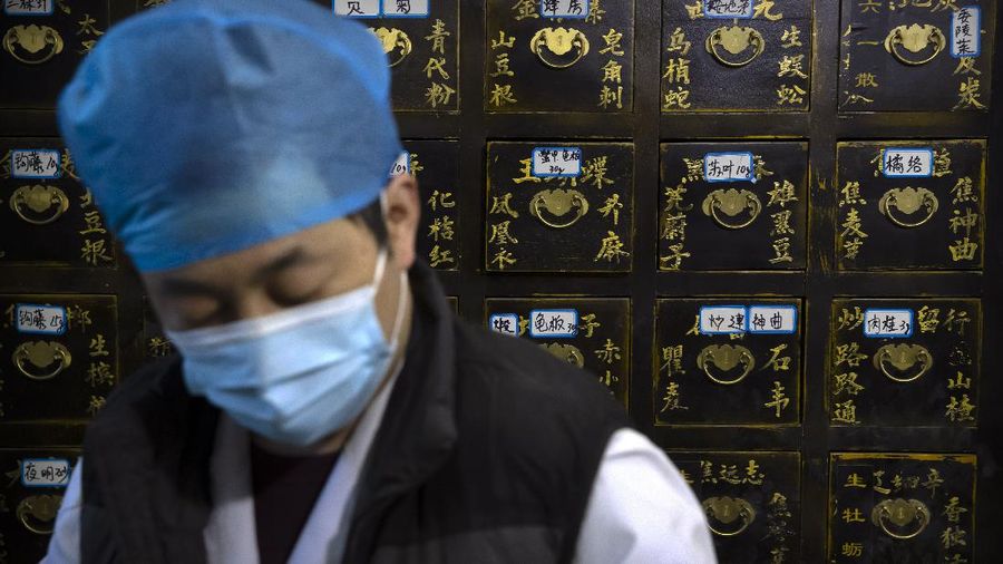 In this March 13, 2020 photo, bowls containing prescriptions for traditional Chinese medicine preparations are stacked on a counter at the Bo Ai Tang traditional Chinese medicine clinic in Beijing. With no approved drugs for the new coronavirus, some people are turning to alternative medicines, often with governments promoting them. (AP Photo/Mark Schiefelbein)