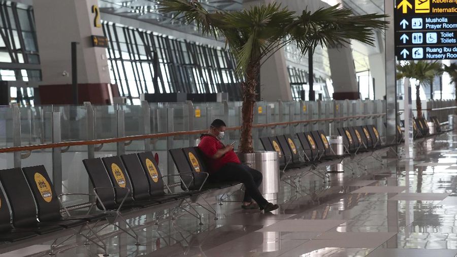 A man sits an empty arrival gate at Soekarno-Hatta International Airport in Tangerang, Indonesia, Indonesia on Friday, April 24, 2020. Indonesia is suspending passenger flights and rail service as it restricts people in the world's most populous Muslim nation from traveling to their hometowns during the Islamic holy month of Ramadan because of the coronavirus outbreak.(AP Photo/Tatan Syuflana)