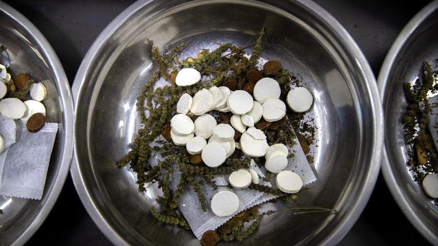 In this March 13, 2020 photo, bowls containing prescriptions for traditional Chinese medicine preparations are stacked on a counter at the Bo Ai Tang traditional Chinese medicine clinic in Beijing. With no approved drugs for the new coronavirus, some people are turning to alternative medicines, often with governments promoting them. (AP Photo/Mark Schiefelbein)