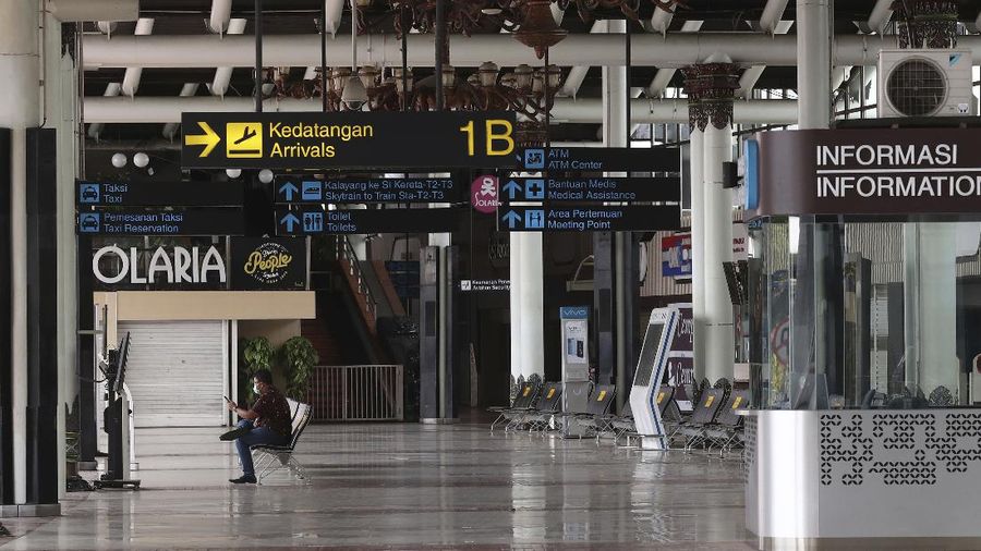 A man sits an empty arrival gate at Soekarno-Hatta International Airport in Tangerang, Indonesia, Indonesia on Friday, April 24, 2020. Indonesia is suspending passenger flights and rail service as it restricts people in the world's most populous Muslim nation from traveling to their hometowns during the Islamic holy month of Ramadan because of the coronavirus outbreak.(AP Photo/Tatan Syuflana)