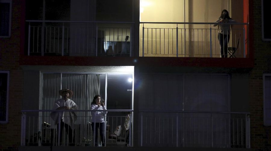 Residents watch a movie from their apartments during a lockdown to help contain the spread of the new coronavirus in Bogota, Colombia, Wednesday, April 22, 2020. The company Cine Colombia set up a giant screen so that people can enjoy a movie projected outside from the comfort and safety of their apartment balconies. (AP Photo/Fernando Vergara)