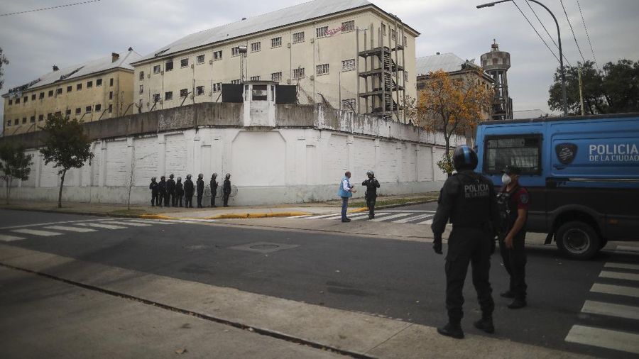 Rioting inmates stand on the roof of the Villa Devoto prison as they protest against authorities who they say are not doing enough to prevent the spread of the new coronavirus, in Buenos Aires, Argentina, Friday, April 24, 2020. (AP Photo/Natacha Pisarenko)