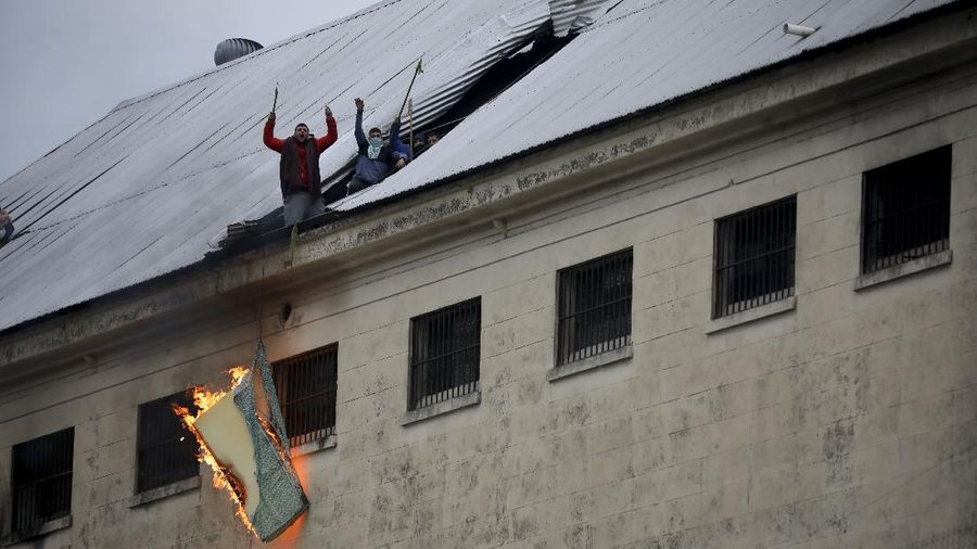 Rioting inmates stand on the roof of the Villa Devoto prison as they protest against authorities who they say are not doing enough to prevent the spread of the new coronavirus, in Buenos Aires, Argentina, Friday, April 24, 2020. (AP Photo/Natacha Pisarenko)