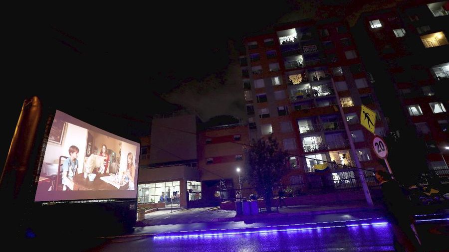 Residents watch a movie from their apartments during a lockdown to help contain the spread of the new coronavirus in Bogota, Colombia, Wednesday, April 22, 2020. The company Cine Colombia set up a giant screen so that people can enjoy a movie projected outside from the comfort and safety of their apartment balconies. (AP Photo/Fernando Vergara)