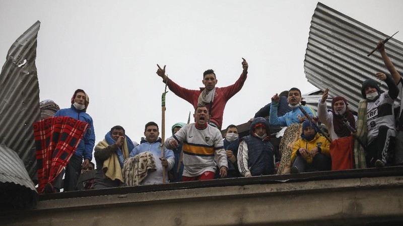 Rioting inmates stand on the roof of the Villa Devoto prison as they protest against authorities who they say are not doing enough to prevent the spread of the new coronavirus, in Buenos Aires, Argentina, Friday, April 24, 2020. (AP Photo/Natacha Pisarenko)