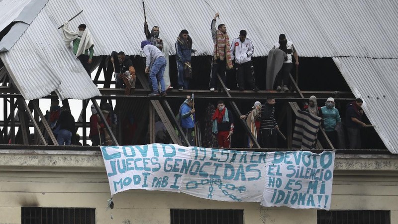 Rioting inmates stand on the roof of the Villa Devoto prison as they protest against authorities who they say are not doing enough to prevent the spread of the new coronavirus, in Buenos Aires, Argentina, Friday, April 24, 2020. (AP Photo/Natacha Pisarenko)