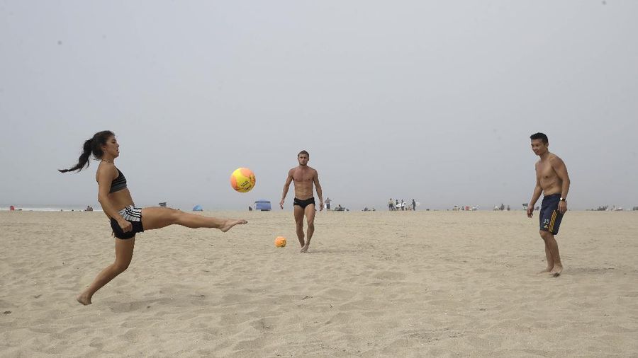 Warga Amerika Serikat berjalan-jalan di Pantai Huntington, California, meski sedang terjadi wabah virus corona. AP/Marcio Jose Sanchez
