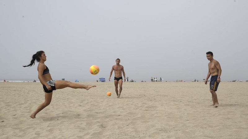 Warga Amerika Serikat berjalan-jalan di Pantai Huntington, California, meski sedang terjadi wabah virus corona. AP/Marcio Jose Sanchez
