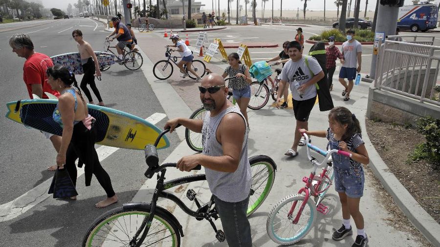 Warga Amerika Serikat berjalan-jalan di Pantai Huntington, California, meski sedang terjadi wabah virus corona. AP/Marcio Jose Sanchez